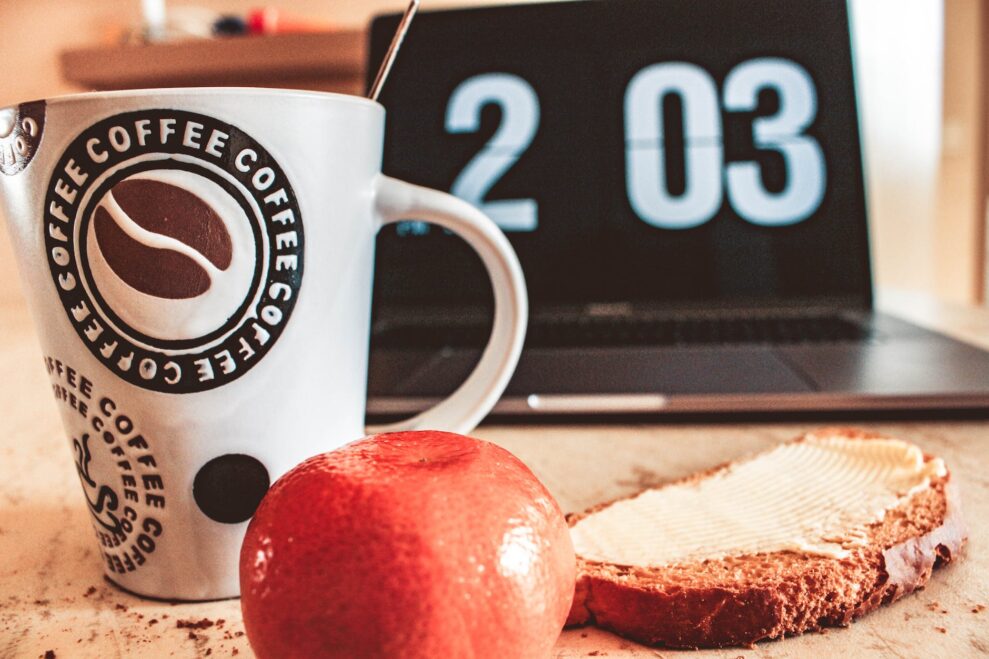 closeup photo of white and black printed ceramic mug beside pastry